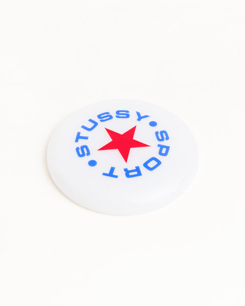 クリアカラーのStüssy Sport Frisbee Accessories。トップにはブルーのStüssyスポーツアートワークとレッドのスターがプリントされています。