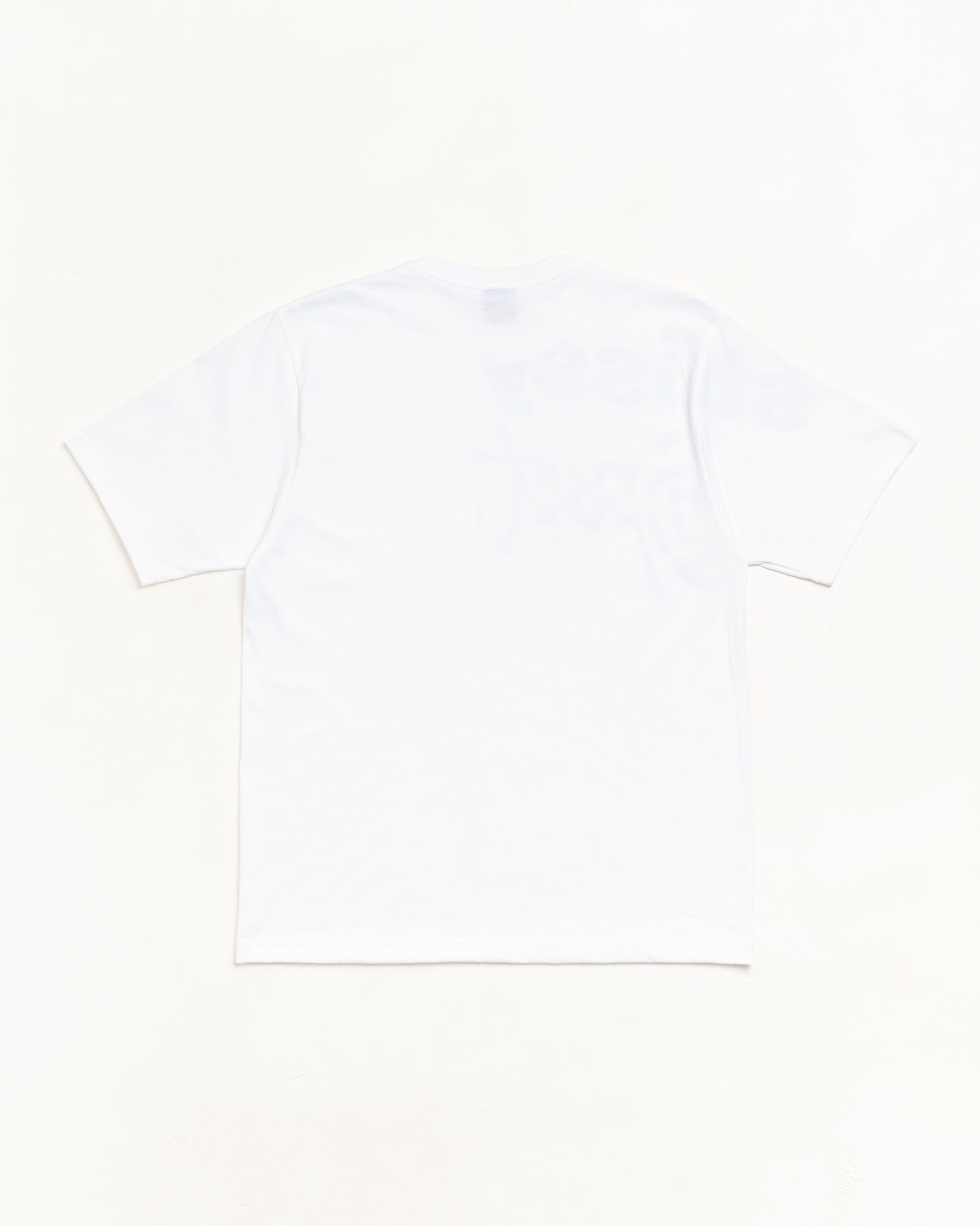 Stüssyのホワイト半袖Tシャツ、バックスタイル。クリーンな無地の背面をフラット置きで撮影した商品画像