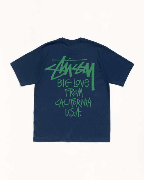 Big Love Tee メンズ ショートスリーブ ネイビー。背面にグリーンのStüssyロゴがスクリーンプリントされた、ミッドウェイトのコットンジャージーTシャツ。